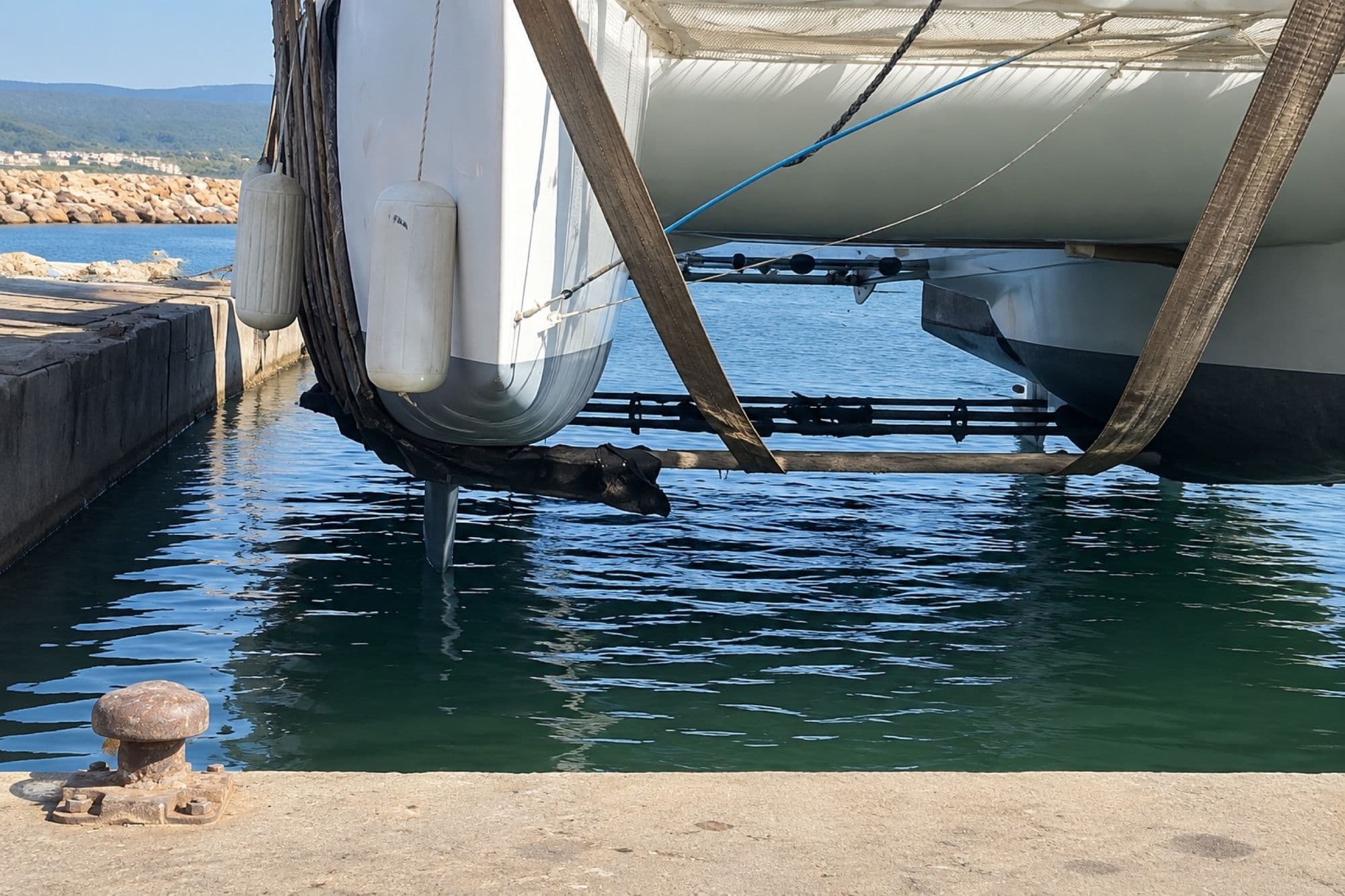 Coque de catamaran soulevée sur sangles au-dessus de l'eau